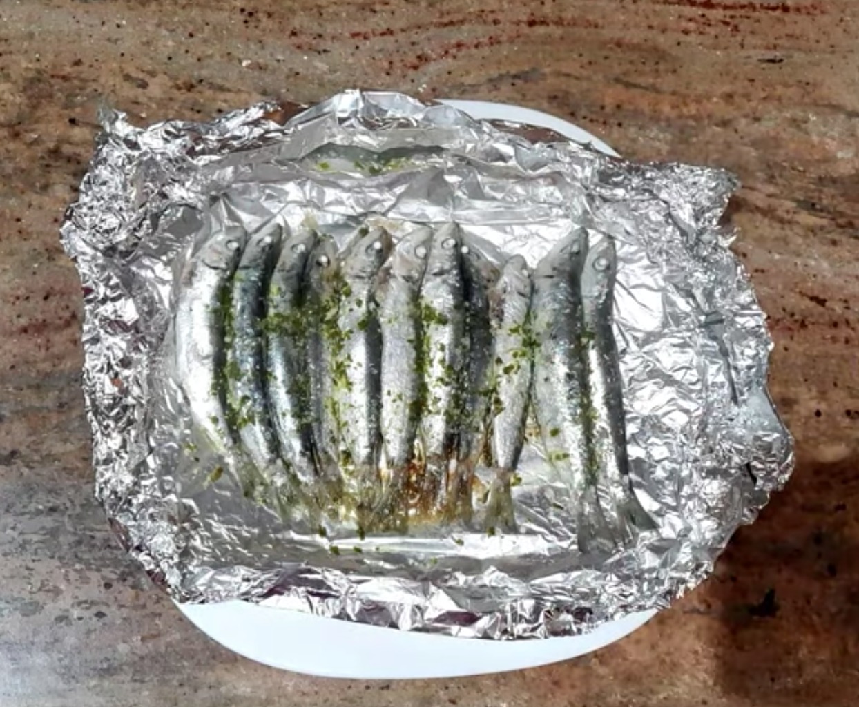 Ensalada de lechuga con cebolla y tomate acompañado de sardinas en Papillote